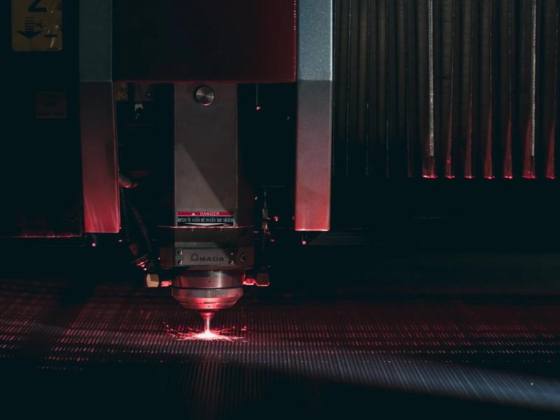 The Amada Ventis fiber laser cutting head at work over sheet steel